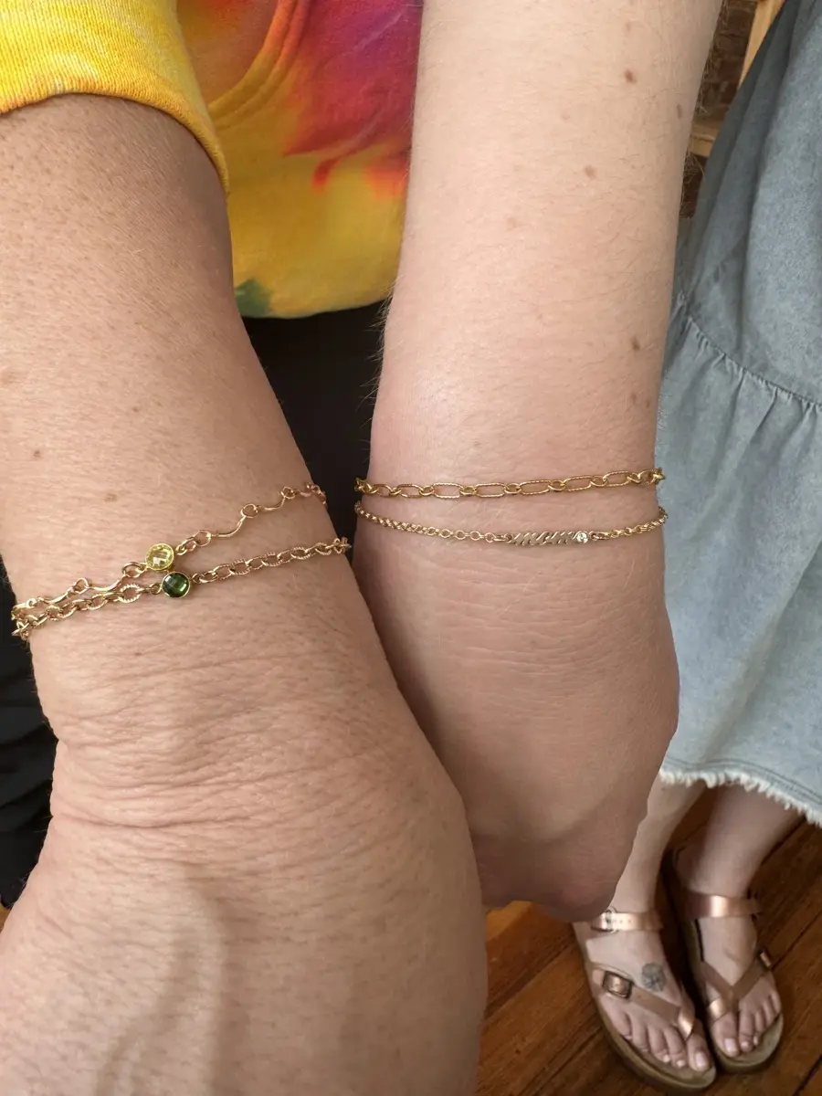 Close-up of two arms and legs showing gold bracelets and sandals.