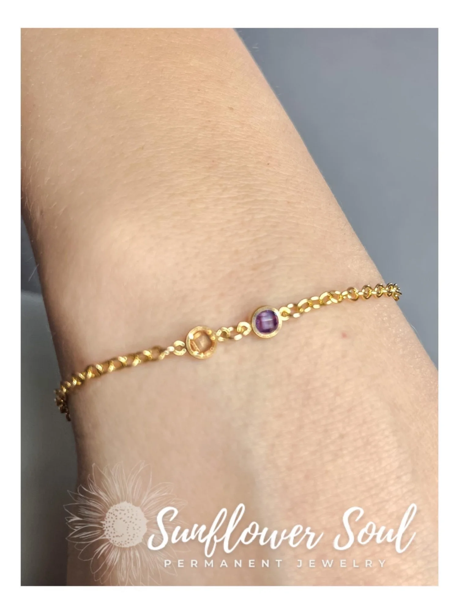Gold bracelet with purple and beige stones worn on a person's wrist.